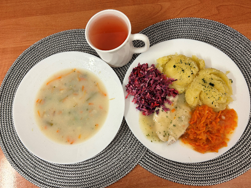 na zdjęciu znajduje się: Jarzynowa z zacierką, Ziemniaki z tłuszczem gotowane, Filet z kurczaka pieczony, Sos pietruszkowy, Surówka wykwintna z olejem, Marchew oprószana z olejem, Kompot owocowy